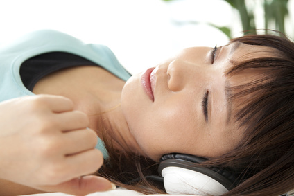 ヘッドフォンで音楽を聴きながら眠る女性